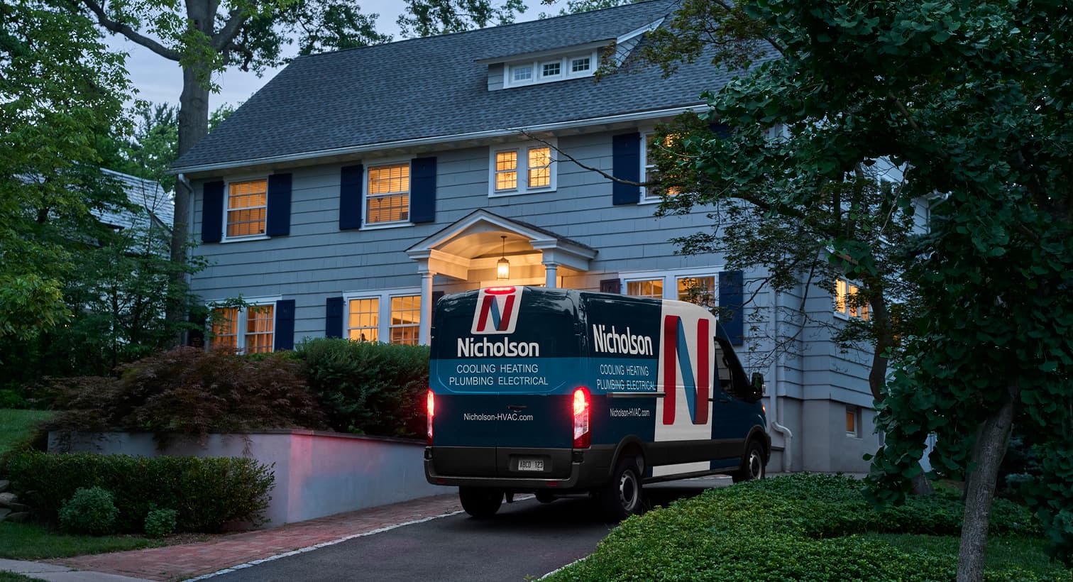 A Nicholson service van parked in a residential driveway at dusk, arriving to provide 24/7 emergency AC repair services.
